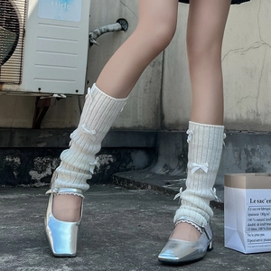 Détail de jambières en tricot crème avec nœuds en satin et chaussures Mary Jane