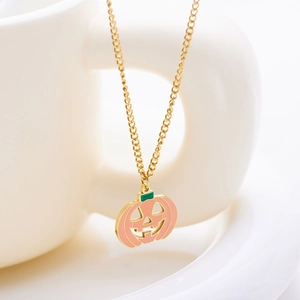 Detail of pink pumpkin pendant with gold chain and green enamel on a white ceramic mug