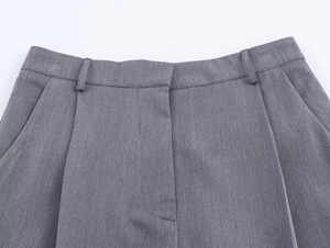 Détail macro du pantalon de costume gris foncé montrant la texture, les passants et les plis