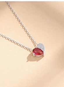 Macro view of heart pendant with red pear-cut zircon and white pavé stones