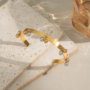Dettaglio di ciondoli a sfera bicolore oro e argento su un bracciale in acciaio lucido