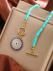 Detailed view of turquoise bead necklace with a crystal-encrusted vintage round pendant
