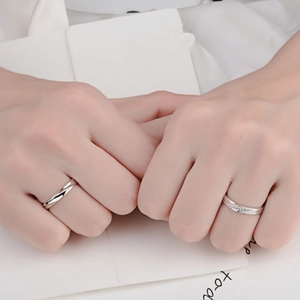 Polished intertwined couple rings in silver finish with pavé stones on woman's band