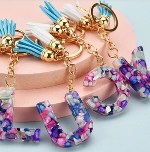Detail of colorful resin letter pendants with suede tassels and gold keyrings