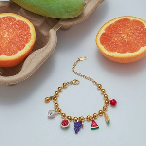 Detail shot of golden beaded bracelet with colorful enamel fruit charms and lobster clasp