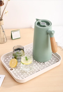 Gros plan d'un pichet isotherme vert avec poignée en bois sur un plateau égouttoir