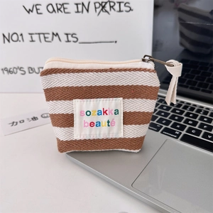 Close-up of striped canvas small makeup bag with brand label on a laptop keyboard