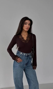Detail of dark coffee slim long-sleeved top with black lace trim on V-neck and cuffs