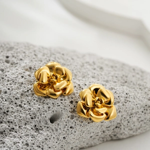 Elegant 18K gold stainless steel camellia stud earrings on a grey stone pedestal