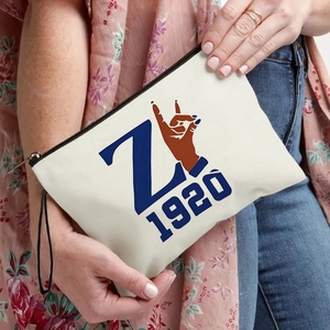 Canvas makeup bag with blue Z 1920 print and zipper closure held by a model