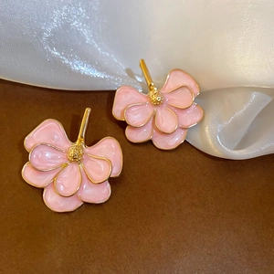 Detail of pink enamel ginkgo flower earrings with gold plating on silk background