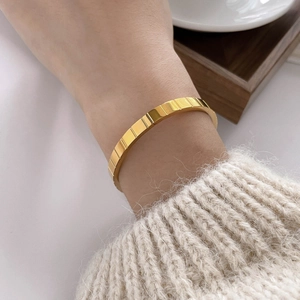Detail shot of golden ice cube textured bracelet paired with a cozy knit sweater cuff