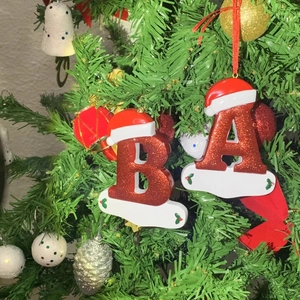 Detail of glittery resin Christmas letter ornaments with Santa hats hanging on a tree