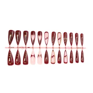 Long almond press-on nails set in burgundy with gold bow chains and cherry patterns