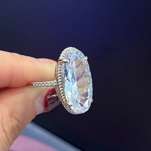 Silver oval cut halo engagement ring with pavé diamonds on a hand model