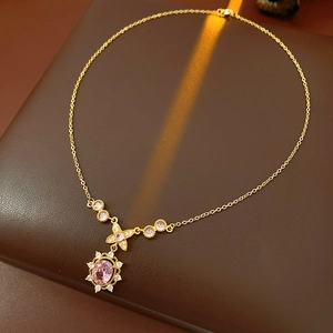 Close-up of vintage gold necklace with pink oval gemstone and zircon snowflake pendant
