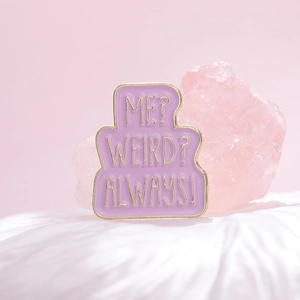 Macro view of purple enamel pin featuring ME? WEIRD? ALWAYS! quote with gold plating