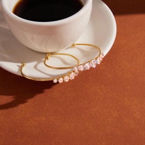 Detail shot of open gold-plated steel bracelets with zircons on a coffee cup