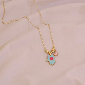Gold beaded necklace with blue Hamsa Hand and pink heart pendant on soft fabric
