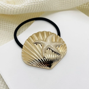 Detail of black elastic hair tie with golden alloy seashell and starfish charms
