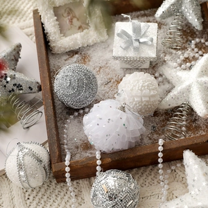 White and silver Christmas ball ornaments set with glitter and pearls in a wooden tray