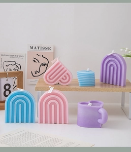 Colorful macaron scented candles in heart and rainbow shapes on minimalist wooden shelves