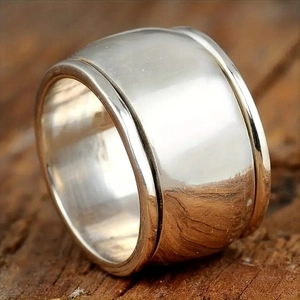 Macro shot of polished wide silver spinning copper ring on a dark rustic wooden background