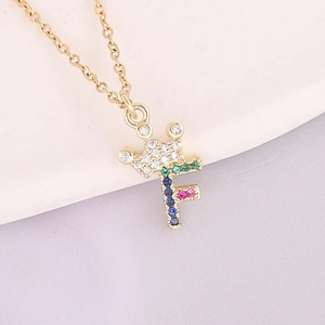 Macro shot of 18K gold letter F crown pendant with colorful inlaid cubic zirconia stones