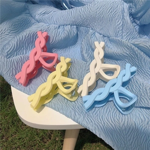 Set of four pastel matte macaron claw clips in pink, yellow, white and blue on grass