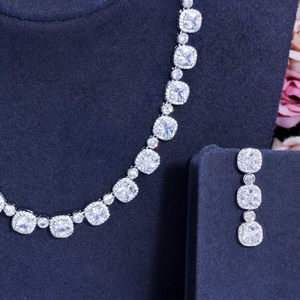 Elegant zircon bridal necklace and drop earrings set on a navy blue velvet display stand