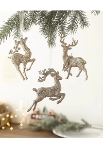 Detailed view of gold glitter reindeer ornaments with white ribbons hanging on pine branches