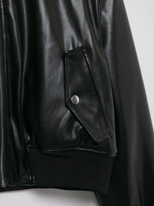 Close-up of black textured leather jacket featuring silver zippers and ribbed hem