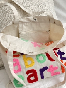 Detail of canvas tote bag showing magnetic buckle closure and inner zipper pocket