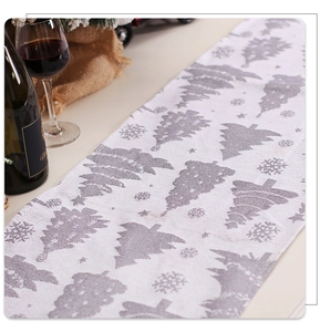 Detail of Christmas table runner with grey snowflake and tree patterns on white fabric