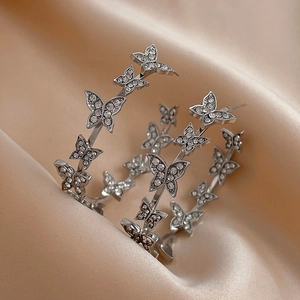 Silver hoop earrings with sparkling crystal butterflies on a soft beige satin background