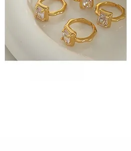 Macro shot of gold-plated lava texture rings with square zircon stones on a white tray