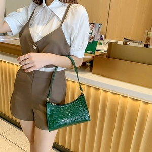 Vintage dark green crocodile pattern baguette bag with gold buckle on female shoulder
