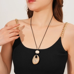 Close-up of a long wax cord necklace with a natural stone-textured teardrop pendant