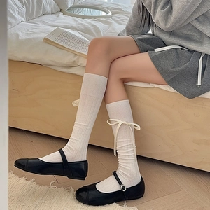 Detailed view of white ribbed calf socks with sweet ribbon bow and black Mary Jane shoes