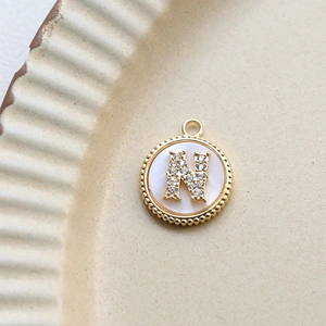 Macro detail of letter N shell pendant with gold plating and cubic zirconia on ceramic