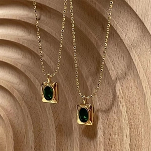 Vintage gold bead necklace featuring a square pendant with a faceted green emerald gem