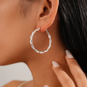 Close-up of silver-tone twisted hoop earring on model showing intricate texture