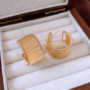 Detailed macro shot of 18k gold plated C-shape earrings with textured winding patterns