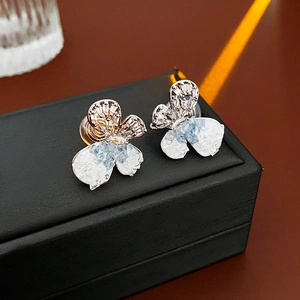 Detailed view of silver butterfly earrings with blue zircons on a jewelry box