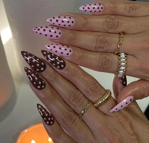 Macro view of long stiletto press-on nails with pink and brown polka dot patterns