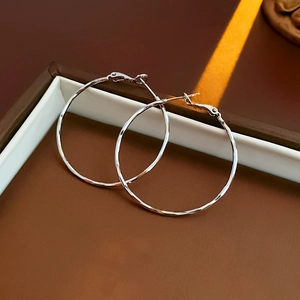 Detail of silver hoop earrings with hammered texture in an elegant brown display box
