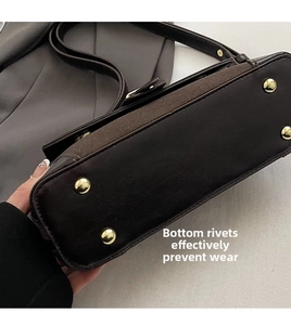 Detail view of the brown shoulder bag bottom featuring four golden anti-wear metal studs