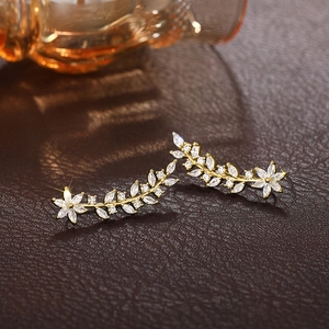 Detailed macro shot of gold flower crawler earrings with marquise zircon stones