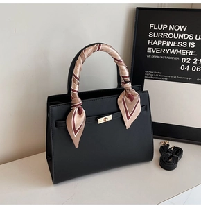 Detail of black PU leather handbag featuring a gold rotary clasp and patterned silk scarf