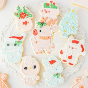 Christmas fondant cookie molds showing reindeer and snowman shapes on a white lace tray